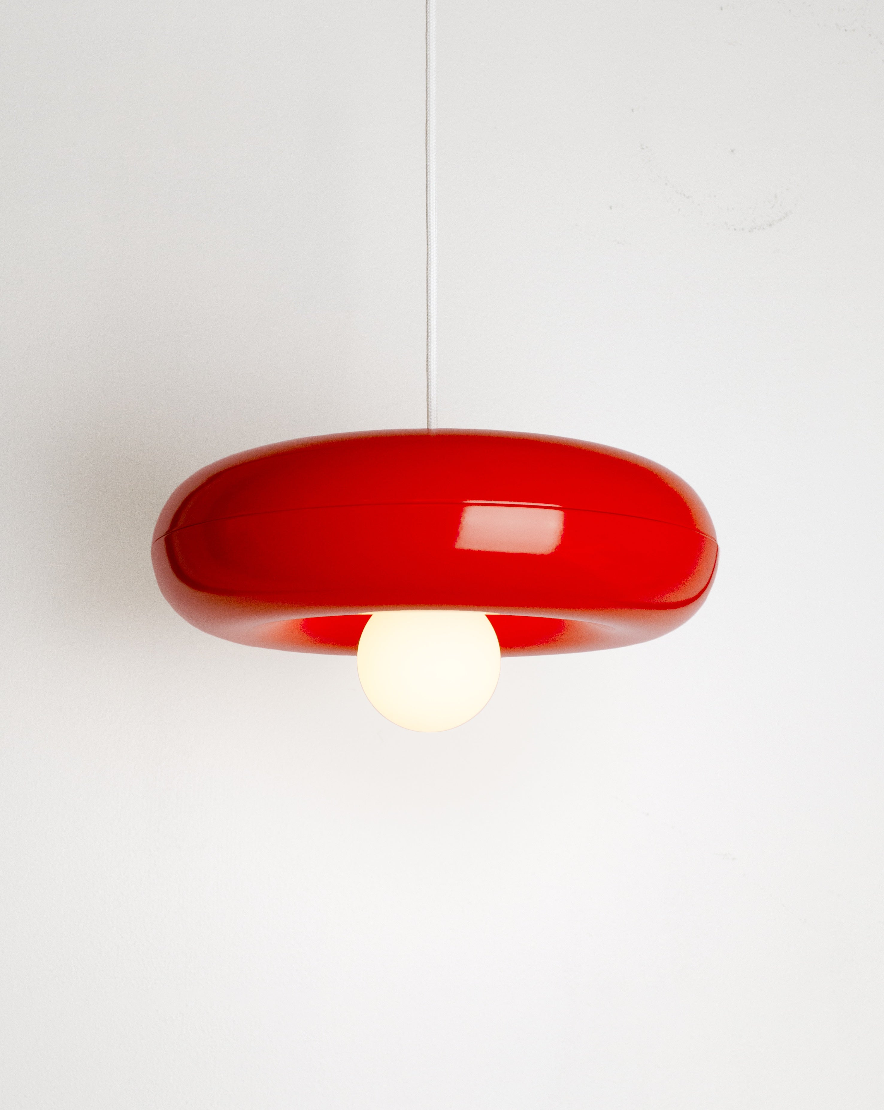 Spin pendant lamp by HAHA studio. The lamp has a round, chubby shape in clear red.