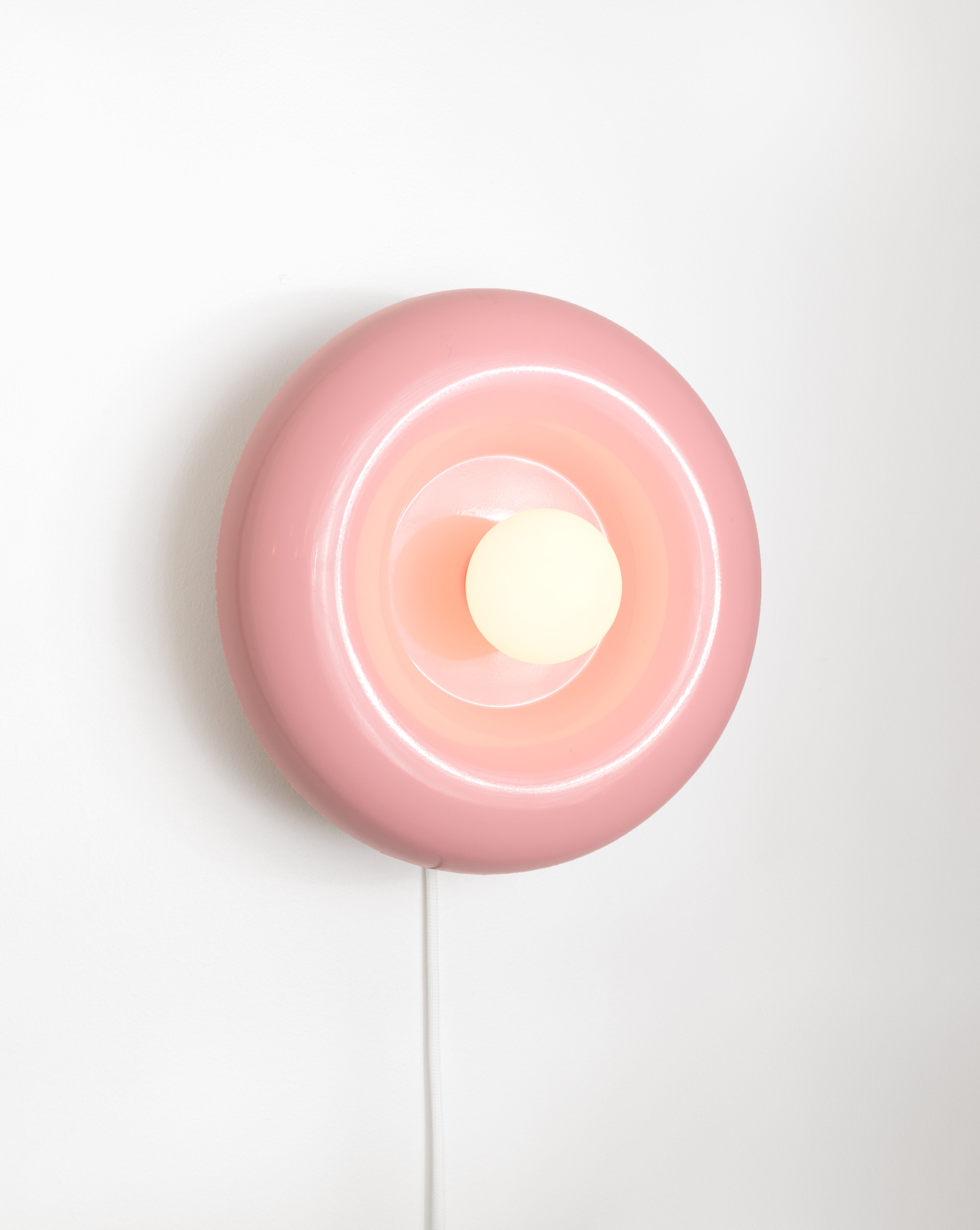 Spin wall lamp by HAHA studio. The lamp has a round, chubby shape in soft pink.