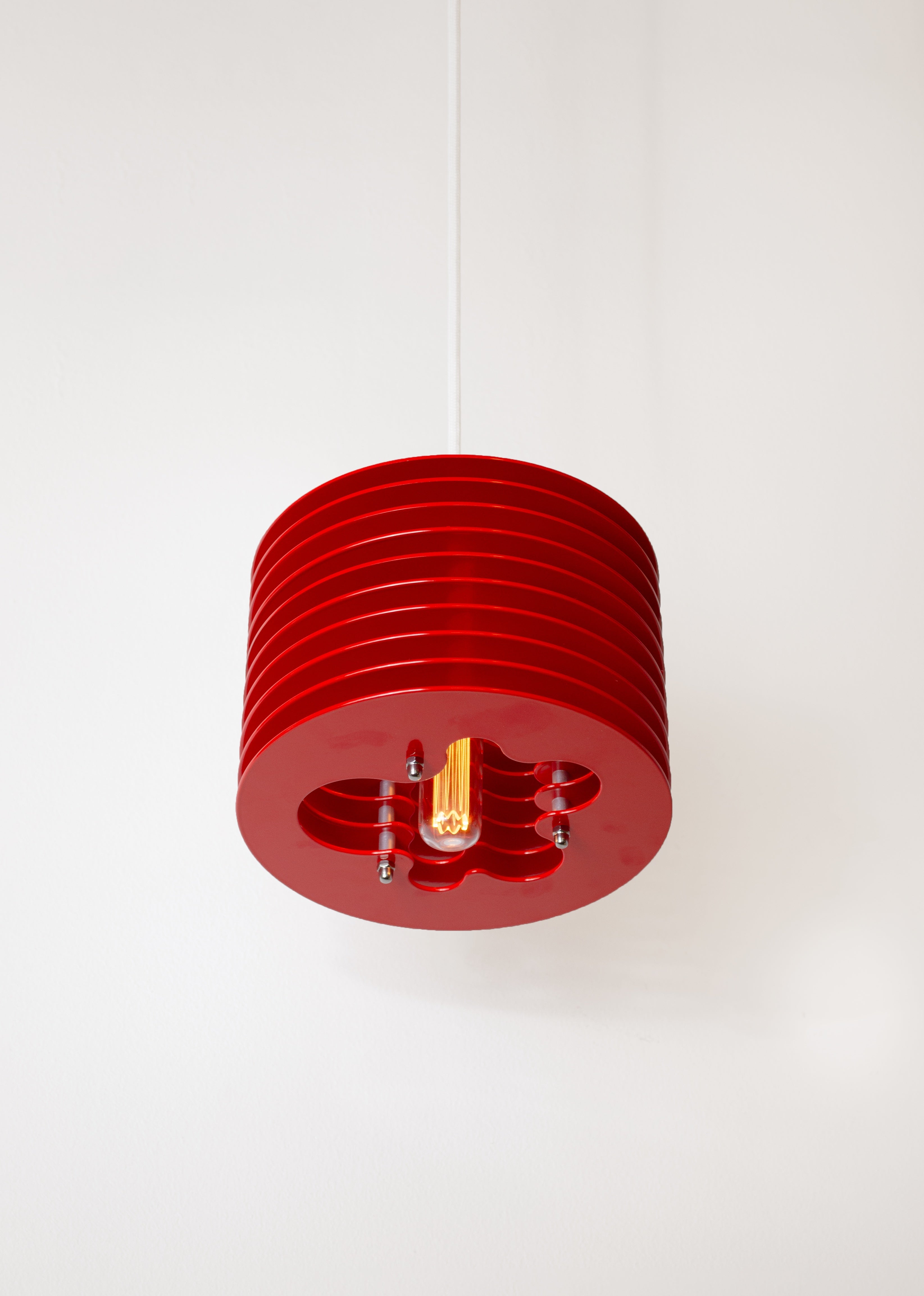 Splash pendant lamp by HAHA studio. Bright red discs assembled with spacing, creating a soft, warm light.