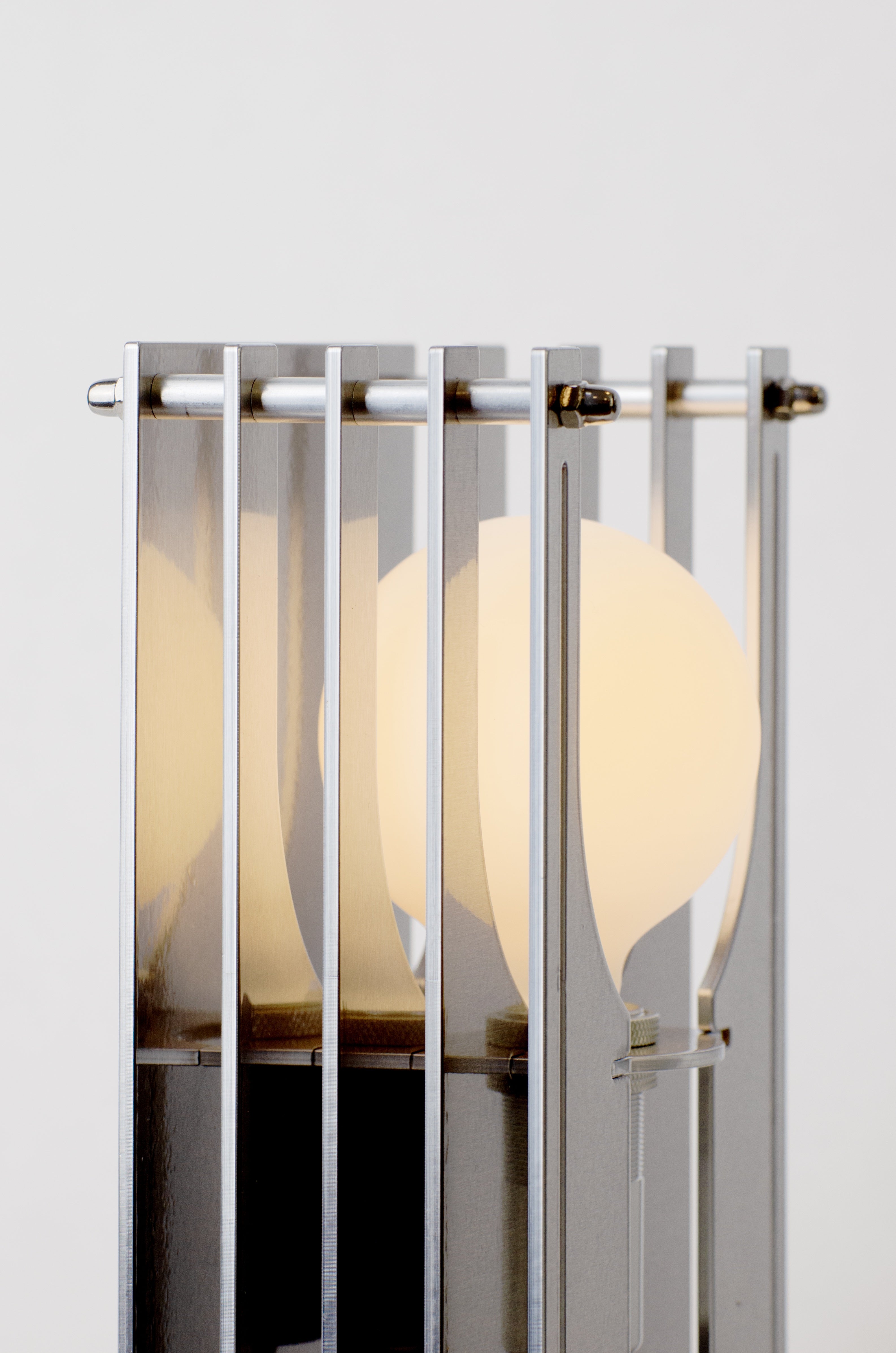 Grid table lamp by HAHA studio. Close-up view showing the layers of the aluminium sheets where the spacing creates a soft, warm light.