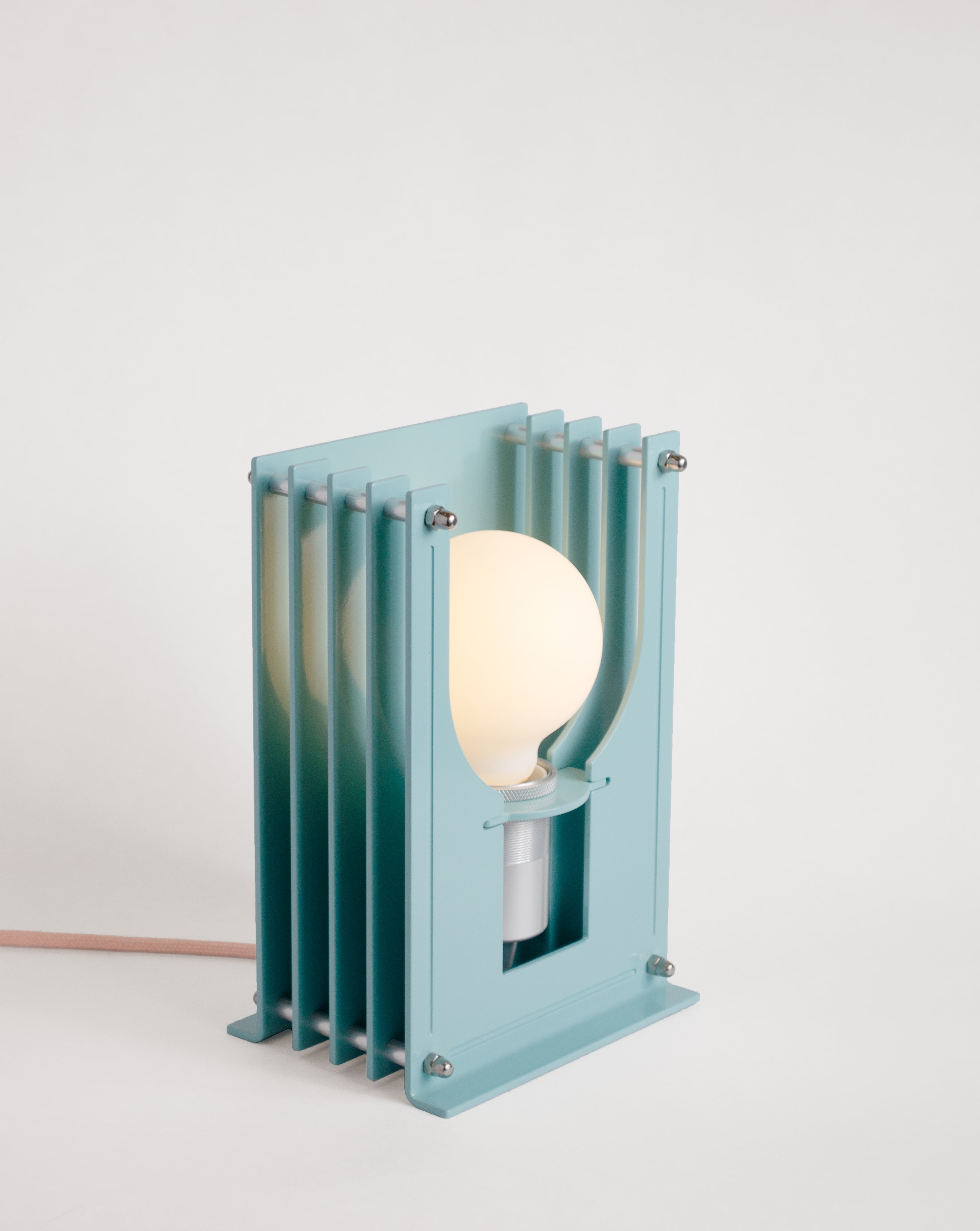 Grid table lamp by HAHA studio. Built from soft turquoise stacked aluminum sheets, where the spacing creates a soft, warm light.