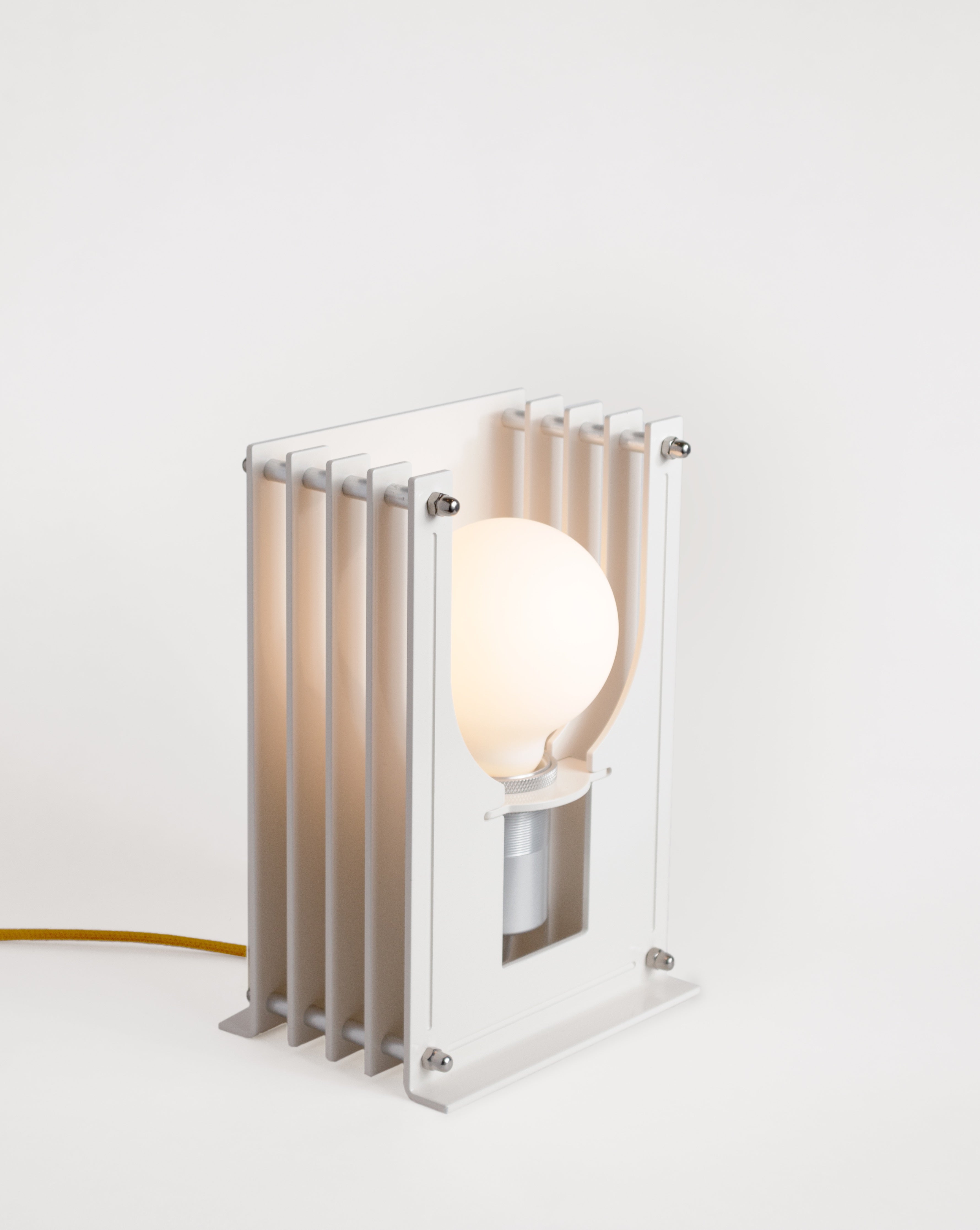 Grid table lamp by HAHA studio. Built from soft off-white stacked aluminum sheets, where the spacing creates a soft, warm light.
